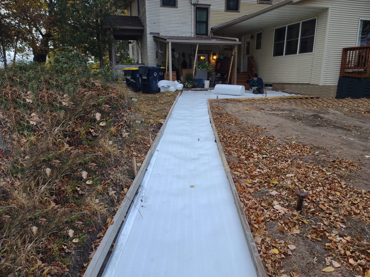 Snow melt going in along a home walkway, with a white Low-E slab shield laid in the trench