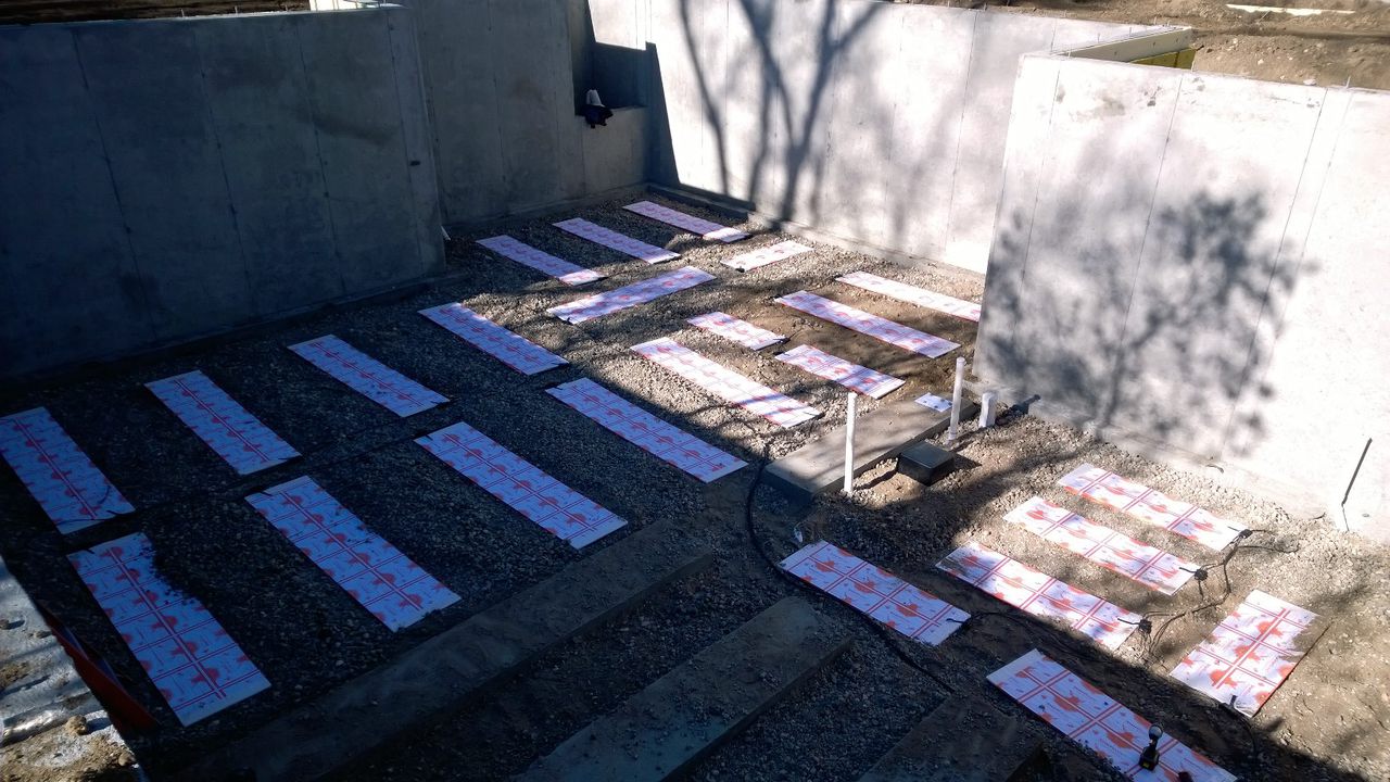 Thermal mass panels laid out on gravel inside a basement foundation
