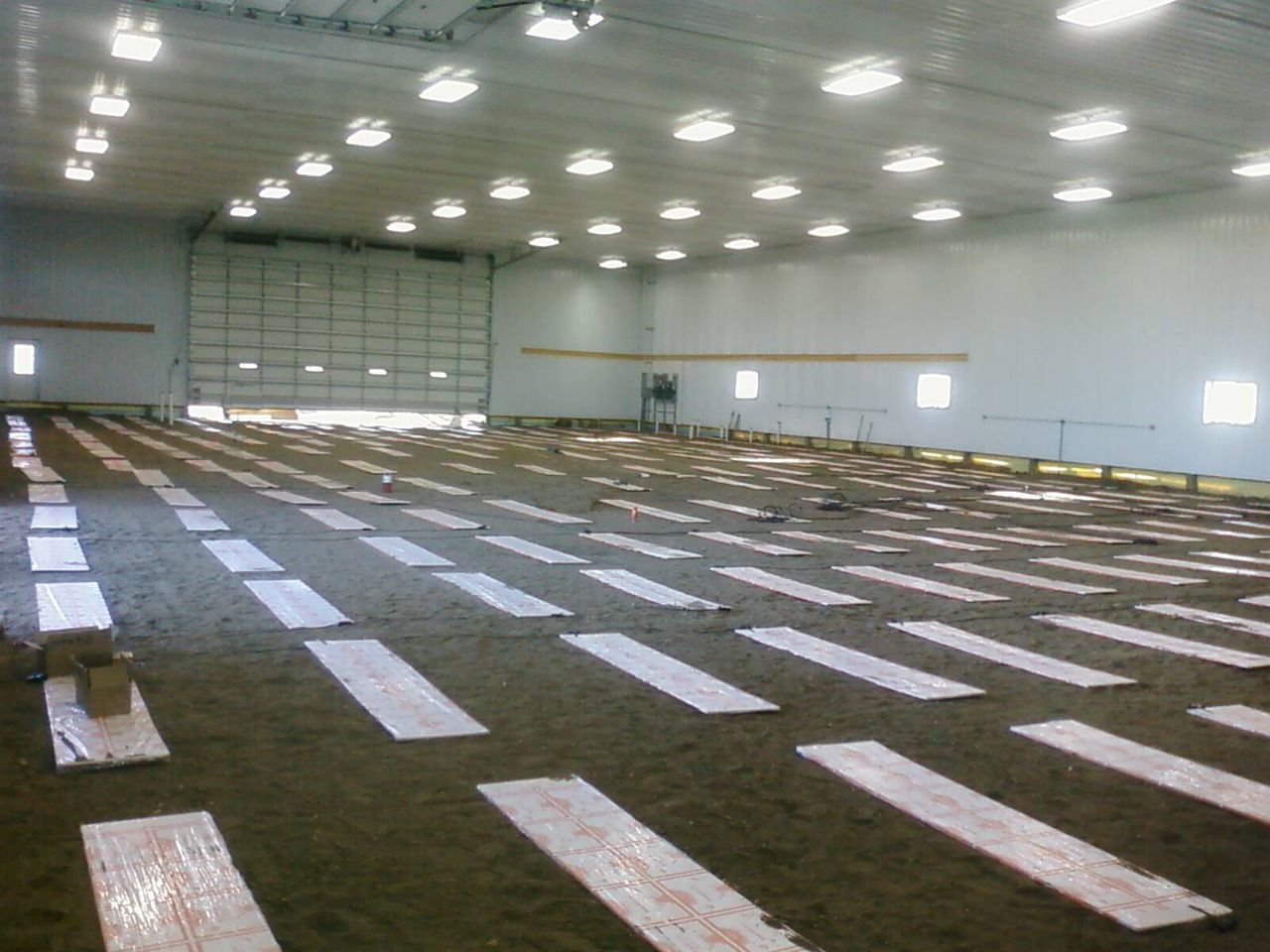 Rows of thermal mass panels across the floor of a large building with overhead doors
