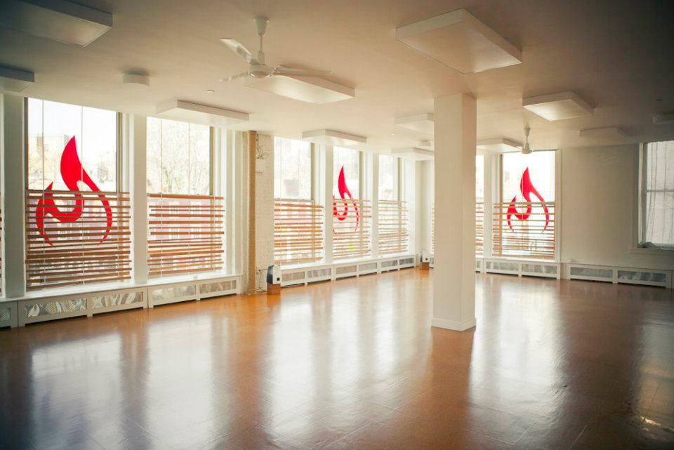 Empty Modo Yoga studio with tall windows and wood floor