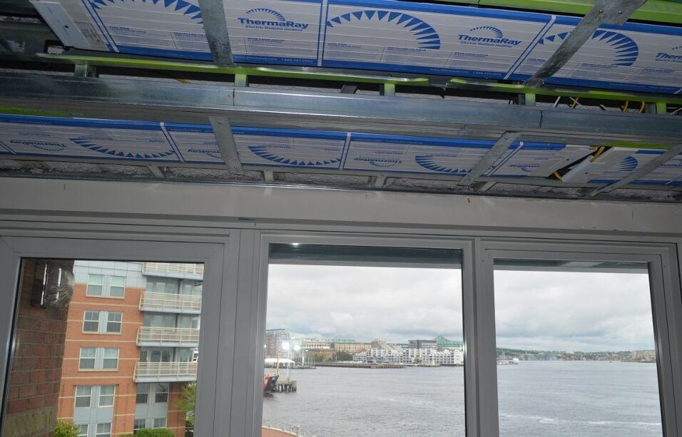 ThermaRay panels between metal ceiling joists above a window wall overlooking Boston Harbor