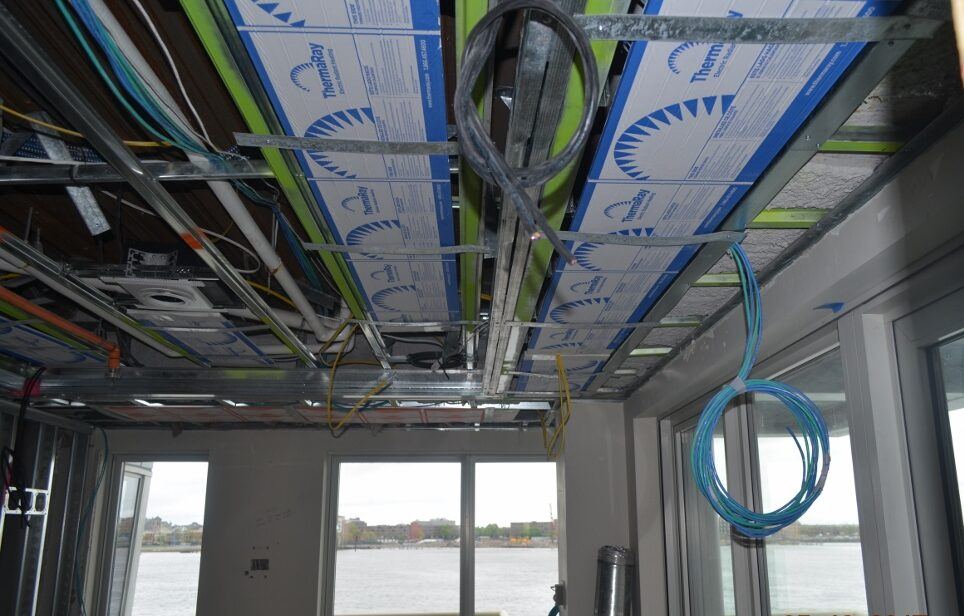 Ceiling panels and wiring above a row of harbor-facing windows before drywall