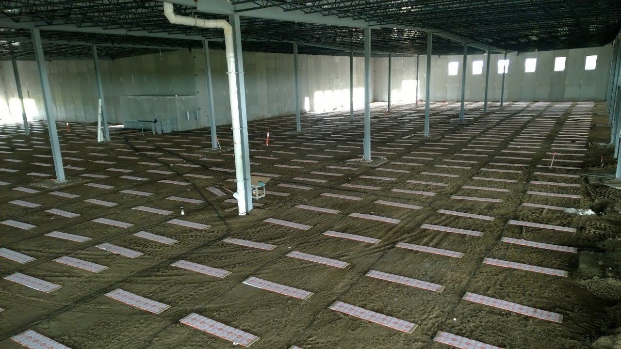 Rows of ThermaRay thermal mass panels laid across the ground inside the Design Ready Controls building before the slab