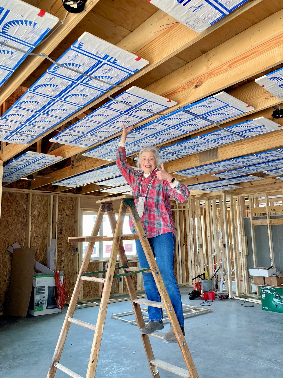 Mary Ellen on a ladder placing radiant ceiling panels between the joists