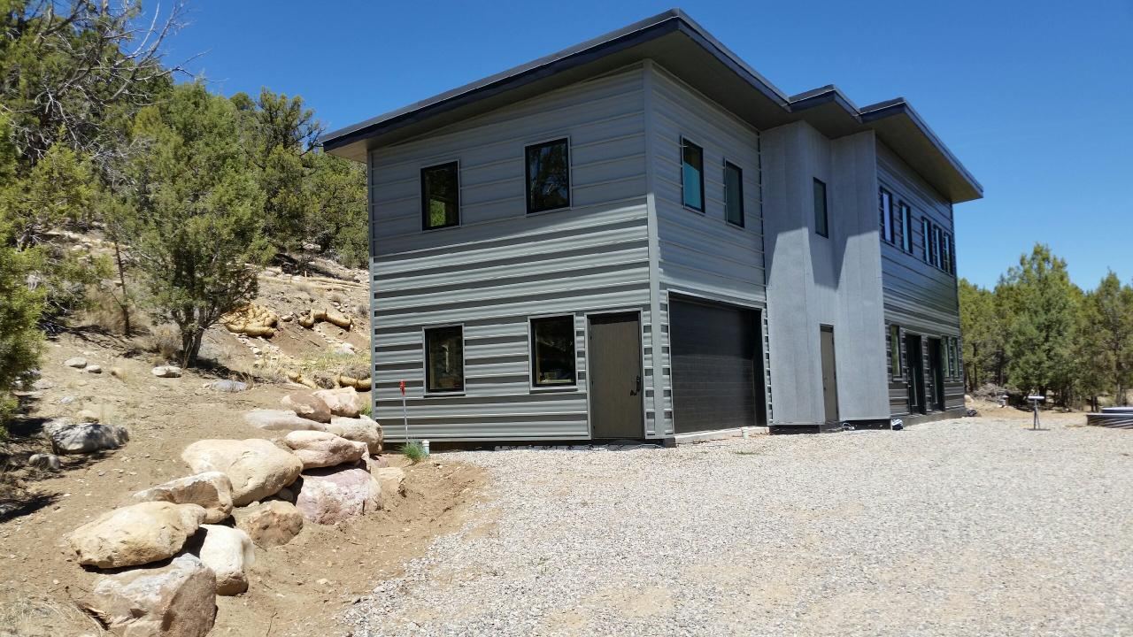 Finished two-story home in Durango with gray siding, set on a rocky hillside