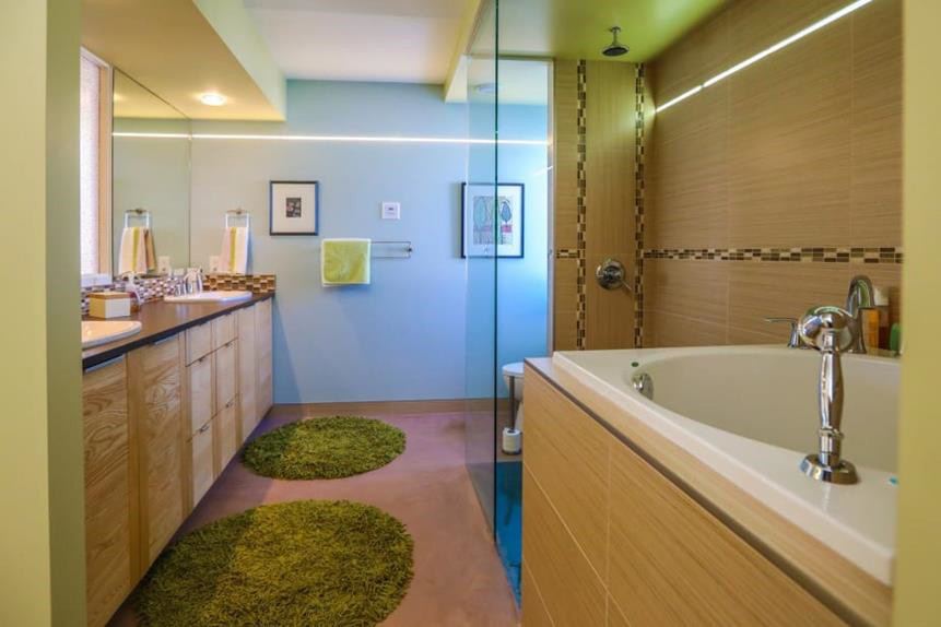 Bathroom with a soaking tub, wood vanity and green rugs