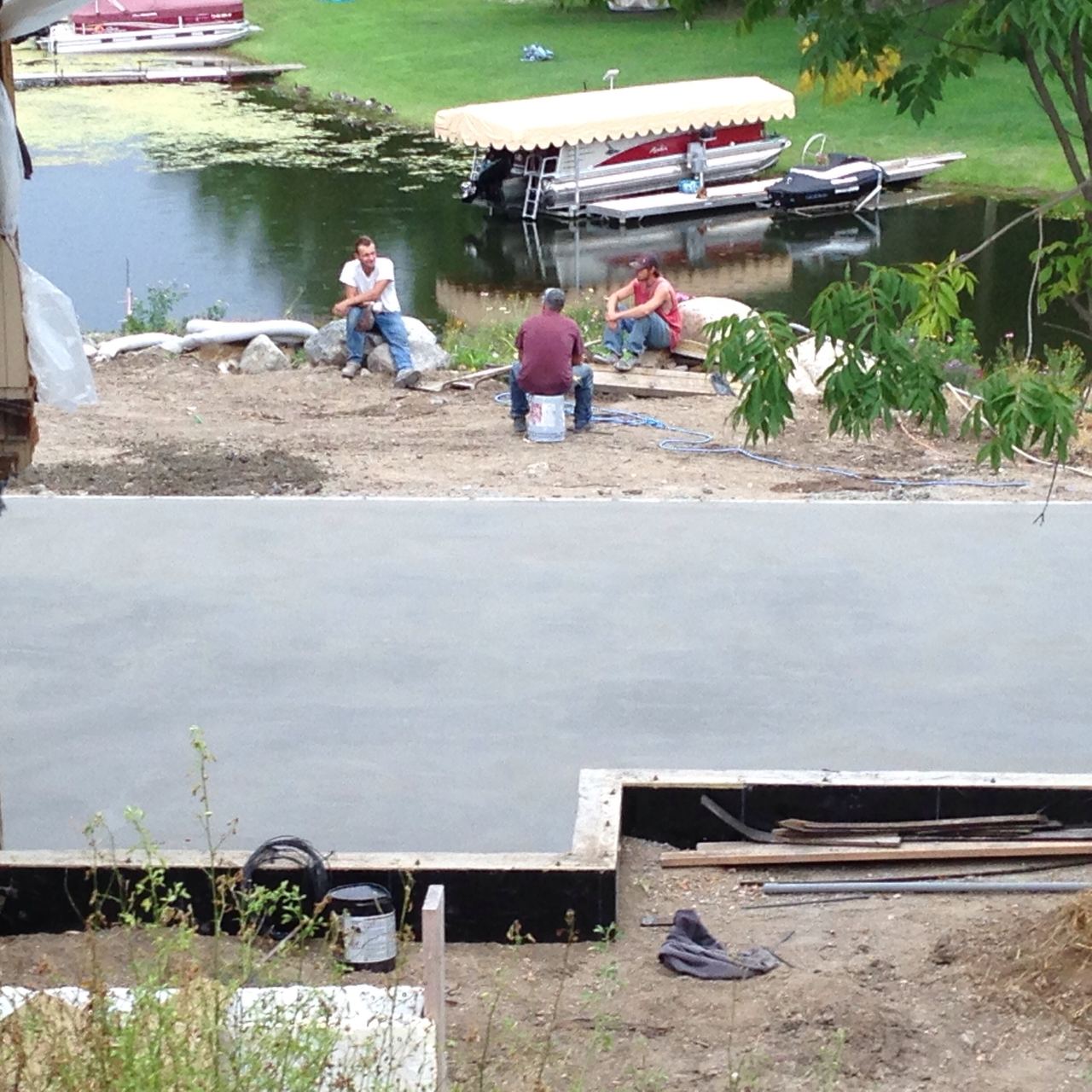 Crew working beside the lake, and the finished slab poured over the heating panels