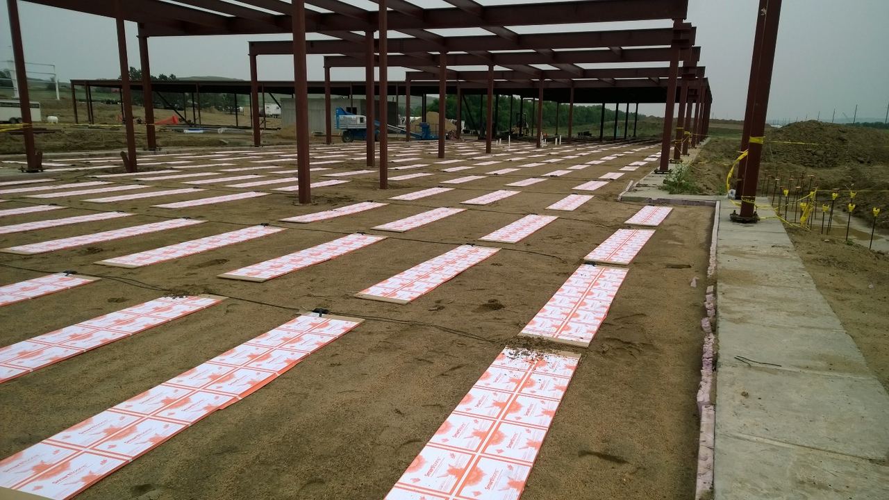 Rows of ThermaRay thermal mass panels on sand inside a steel building frame at McKenzie Electric Coop