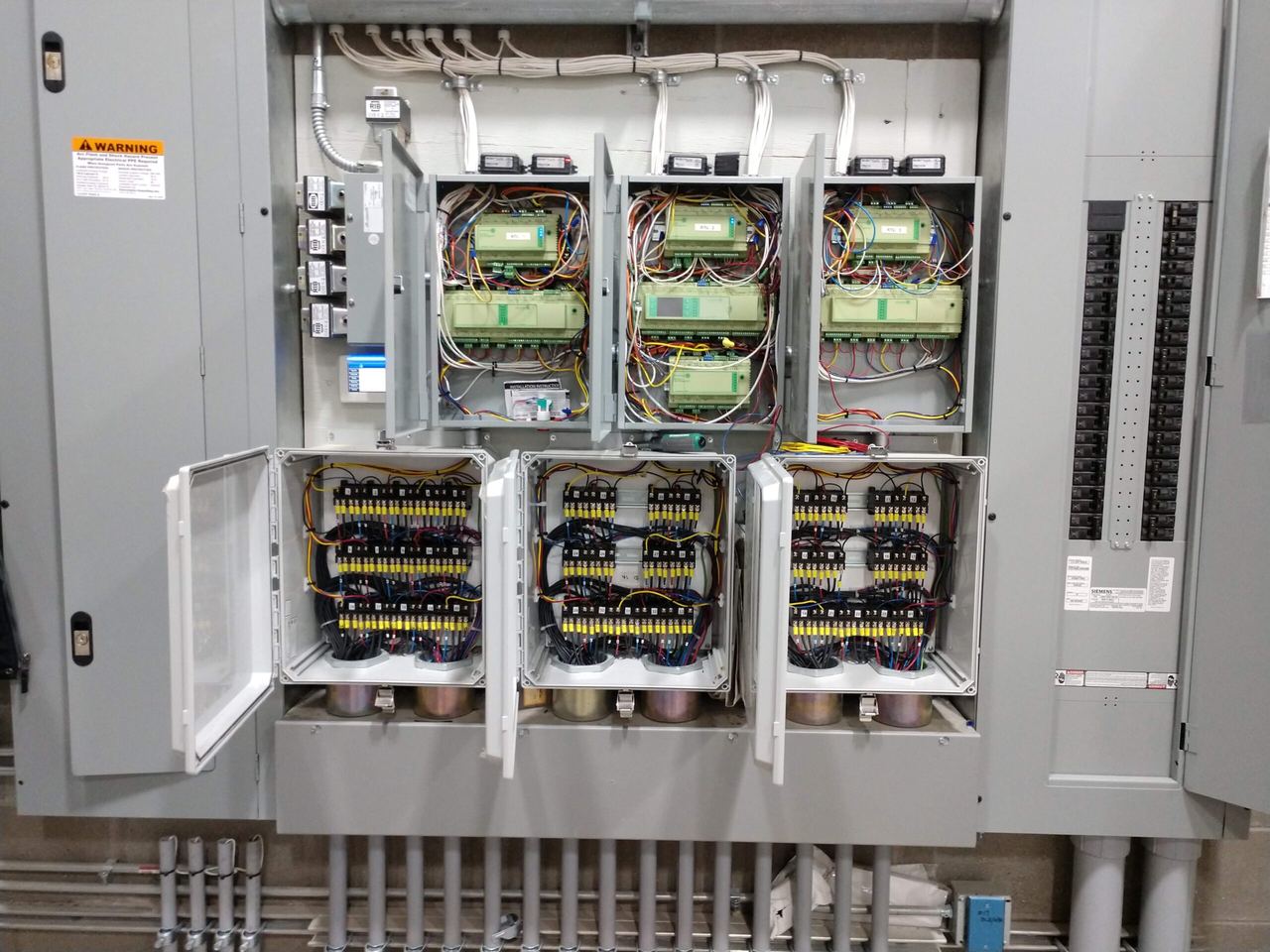 Open electrical cabinets with rows of relays controlling the floor heating circuits