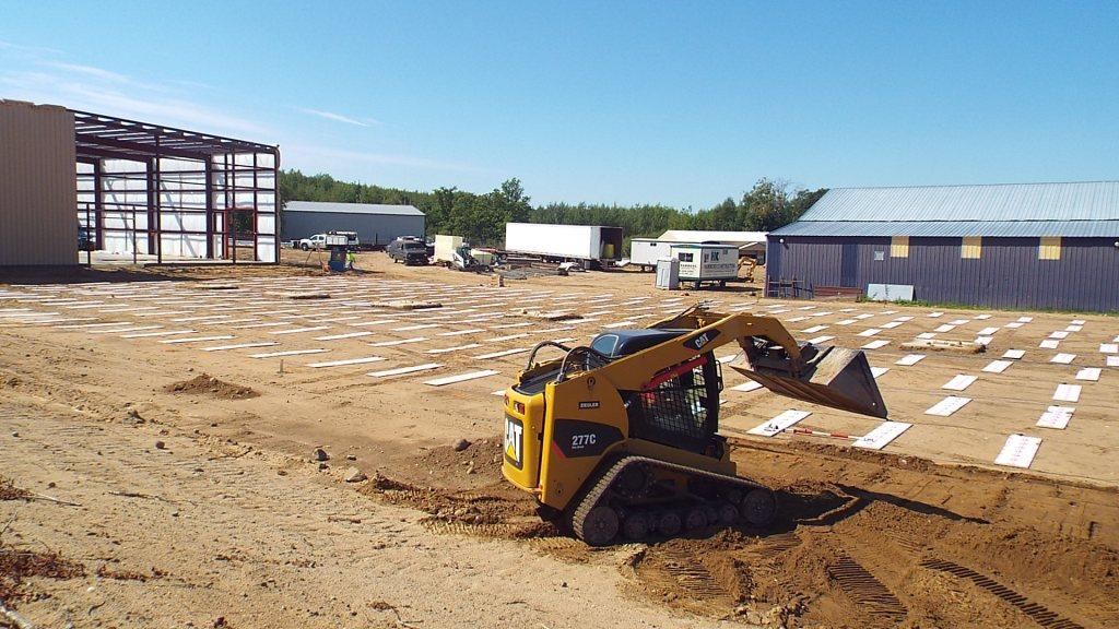 Skid steer spreading fill over the heating panels