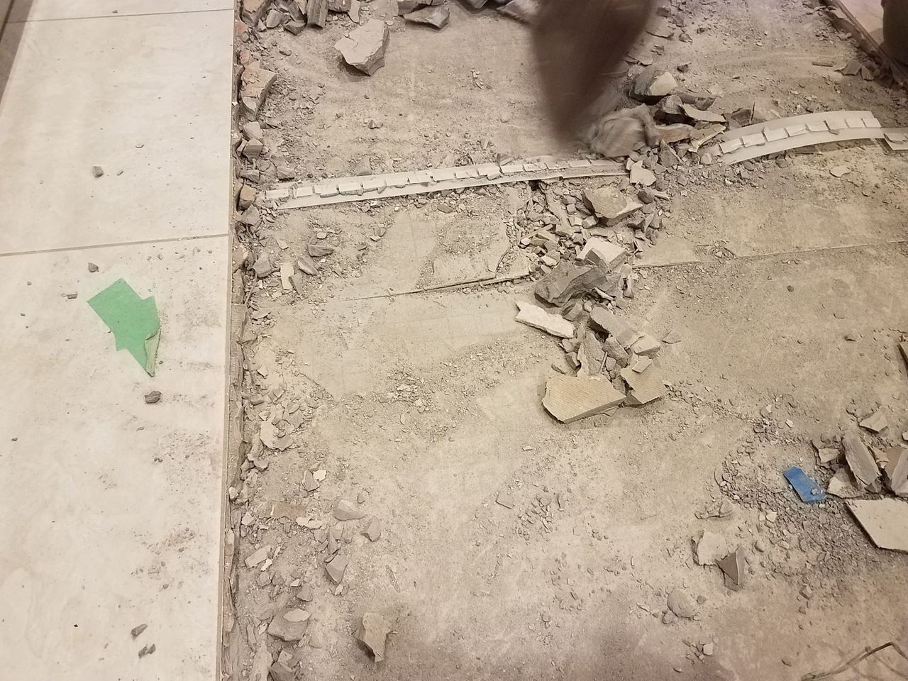 Broken tile and mortar on a torn-up floor during demolition