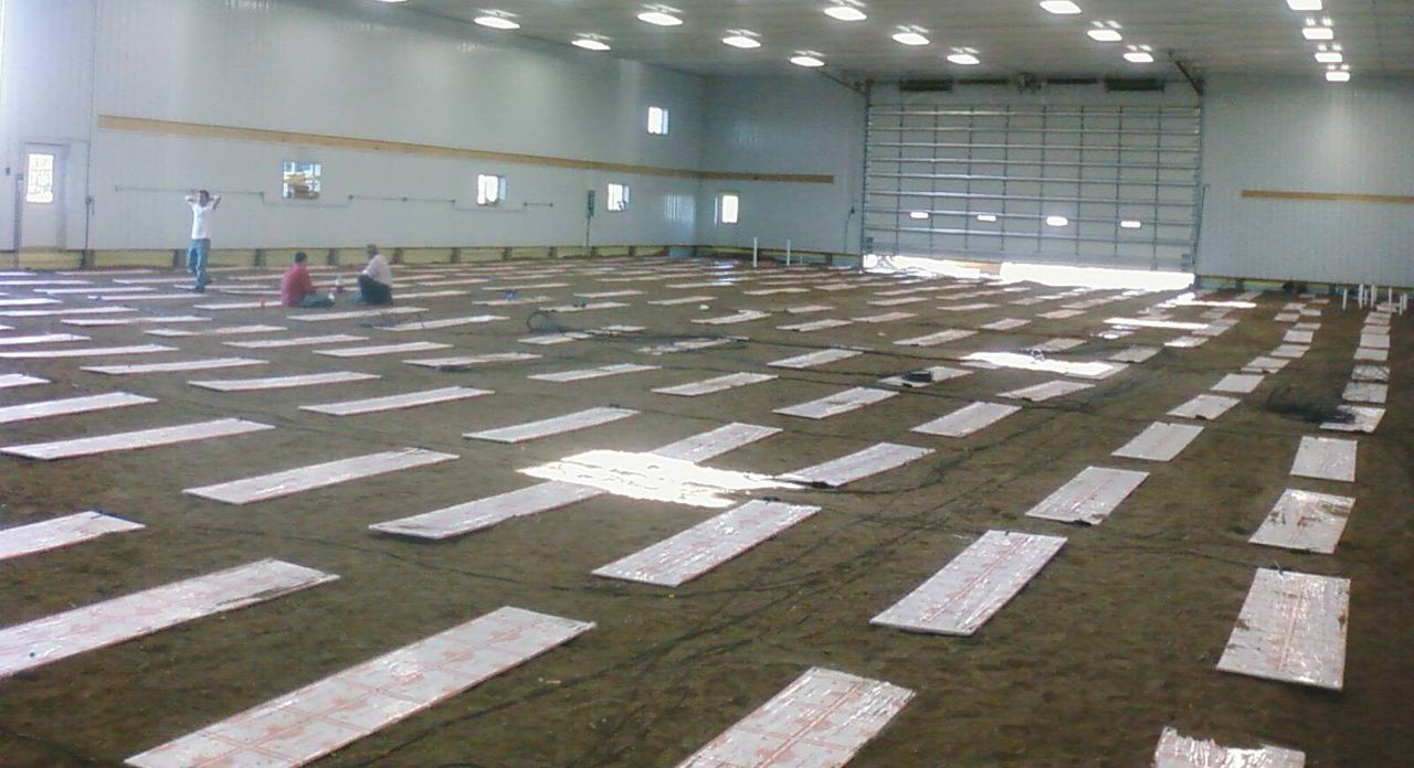 Thermal mass heating panels in rows on sand inside a large building